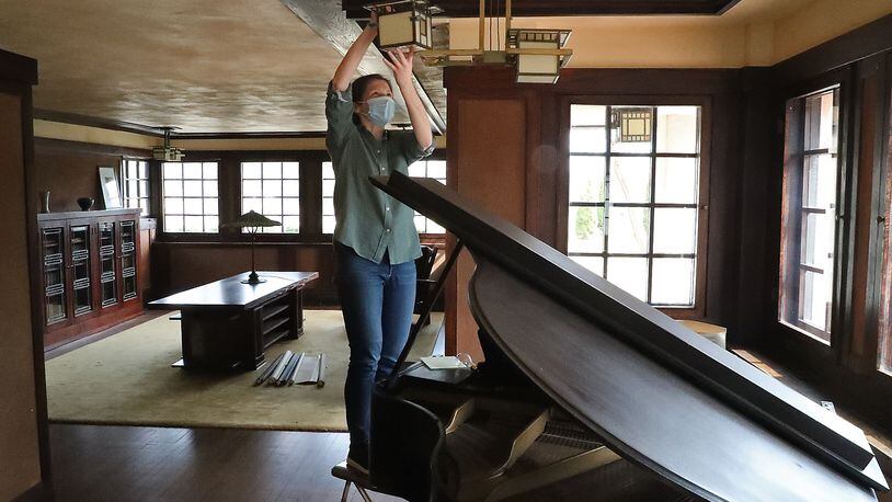 Marta Wojcik, Executive Director and Curator of the Westcott House, cleans a light fixture as she and a handfull of volunteers clean and get the house, designed and built by Frank Lloyd Wright, ready to reopen for tours on Saturday. BILL LACKEY/STAFF