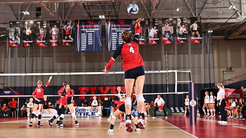 Lexie Almodovar, center, of the Dayton volleyball team, serves during a match against Western Kentucky at the Frericks Center on Friday, Aug. 24, 2023. Photo courtesy of University of Dayton Athletics