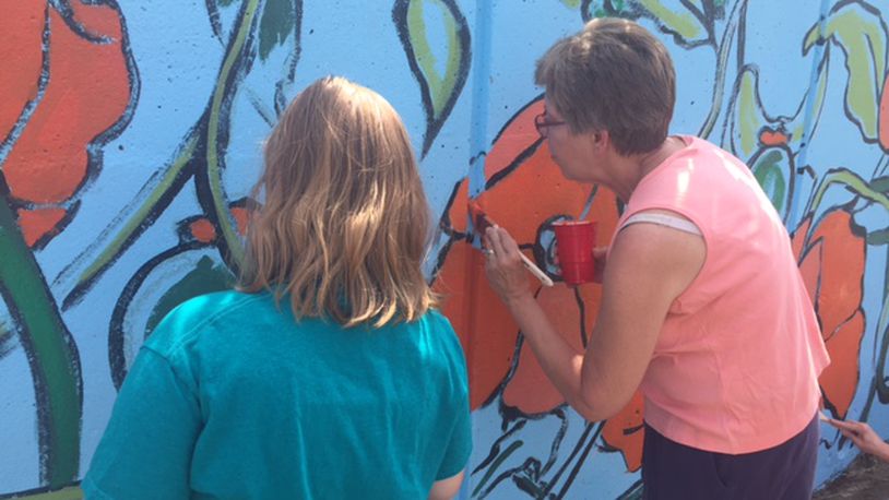 South Park residents and local artists help paint a mural Saturday, June 17, 2017, on the corner of Wayne Avenue and Hickory Street in Dayton.