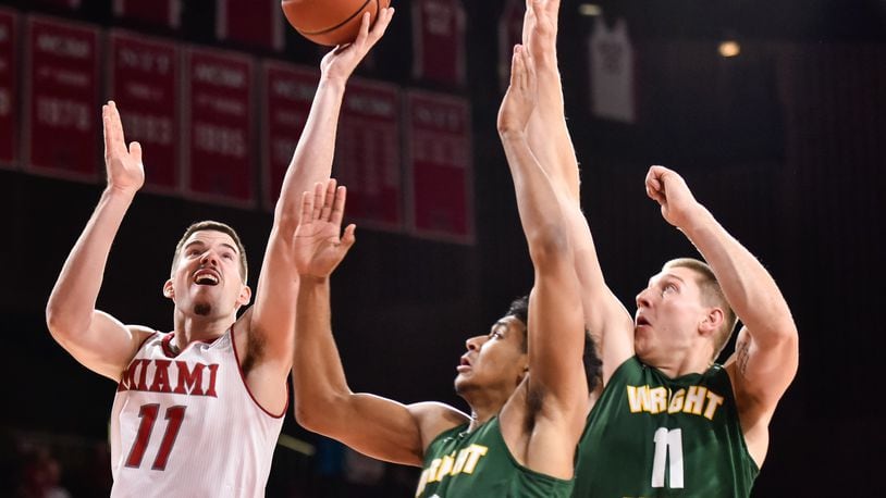 Miami’s Logan McLane (11), left, drives to the hoop defended by Wright State’s Mark Hughes (3) and Loudon Love (11) during their game Tuesday, Nov. 14 at Millett Hall on the Miami University Campus in Oxford. NICK GRAHAM/STAFF