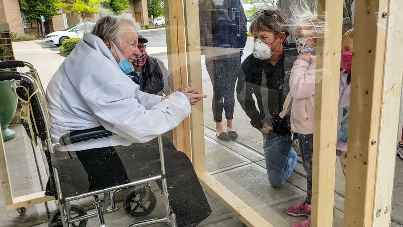 The family of Virginia “Ginny” Meyer, 95, was finally able to see her up close thanks to a clear, protective box the family built to be placed outside Barrington of West Chester senior living facility May 13, 2020. Meyer’s children, grandchildren and great-grandchildren greeted her as she came out the door to see them up close for the first time in over two months due to the coronavirus pandemic. If they wanted to see her before they had to see her from her third floor balcony. NICK GRAHAM / STAFF FILE