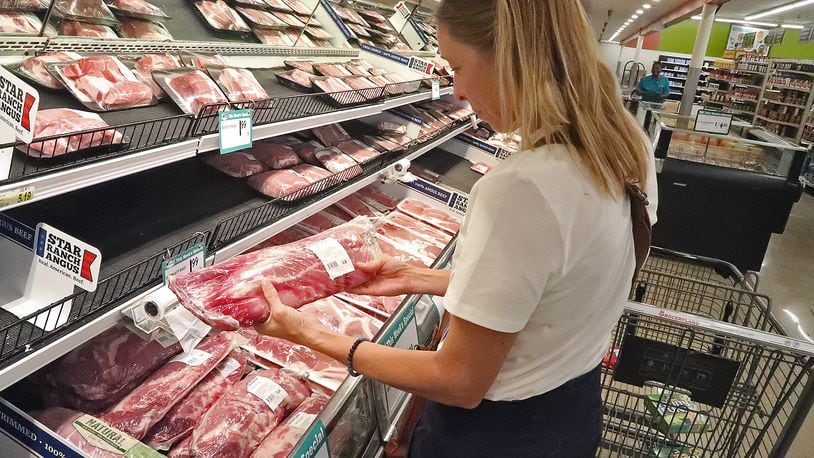 Lori Driskill-Lange looks over the meat at Groceryland on South Limestone Street Thursday. Lori said her family has decided to buy half a cow directly from a farm to help combat the rising price of meat. BILL LACKEY/STAFF