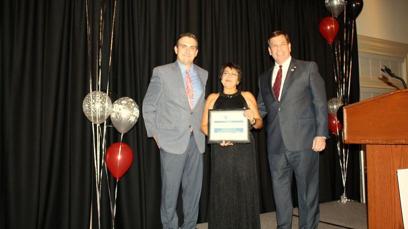 Joe Hinson (right), president and CEO of the West Chester-Liberty Chamber Alliance, presents former Reach Out Lakota CEO/Executive Director Lourdes Ward (center) with a plaque denoting her 25 years of service to the organization and the West Chester/Liberty Township community during the 6th Annual Celebrity Waiter Dinner in 2017. J. Peyton Gravely, Reach Out Lakota’s current CEO/executive director is pictured on the left. CONTRIBUTED