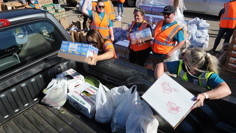 Volunteers load food into the back of a pickup truck during the Dayton Food Bank mass food distribution event. Volunteering at a nonprofit is an example of an act of kindness. MARSHALL GORBY\STAFF