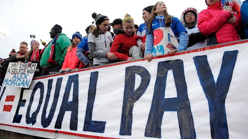 In this April 6, 2016, file photo, fans stand behind a large sign for equal pay for the women’s soccer team during an international friendly soccer match between the United States and Colombia at Pratt & Whitney Stadium at Rentschler Field in East Hartford, Conn. Although weekly earnings for all full-time, salaried workers was up sharply in the first three months of the year, gender and racial pay gaps persist. (AP Photo/Jessica Hill)