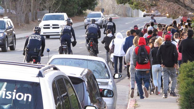 Reno police officers on bicycles escort about 100 protesters as they march 2 miles to the Washoe County School District headquarters to deliver a petition on non-lethal force after a 14-year-old Reno boy was shot last week by a campus police officer, Wednesday, Dec. 14, 2016, in Reno, Nev.. (AP Photo/Scott Sonner)