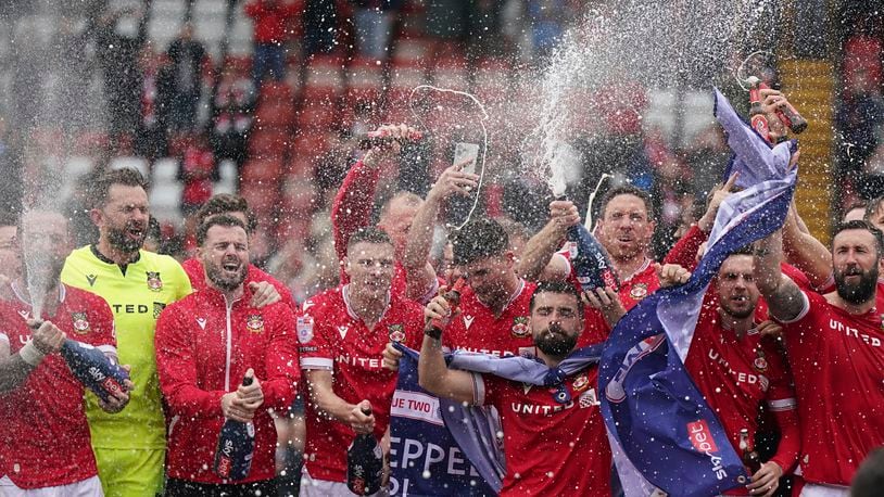 Wrexham players on the pitch celebrate promotion to League One after the final whistle of the Sky Bet League Two match at the SToK Cae Ras, Wrexham, Saturday April 13, 2024. (Jacob King/PA via AP)