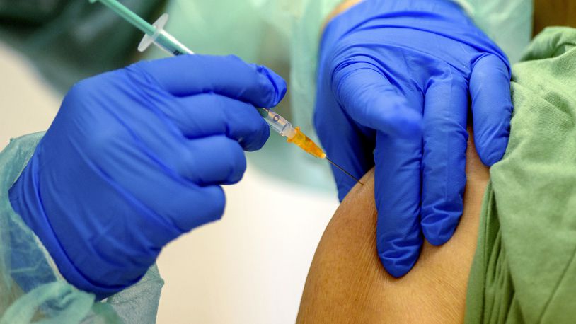 An employee of the vaccination centre of the Salzlandkreis injects a woman with a vaccination dose against the Corona virus in Stassfurt, Germany, Monday, Jan. 11, 2021. Parallel to the tightened Corona rules, vaccination has been intensified in the fight against the pandemic in the German state of Saxony-Anhalt. (Klaus-Dietmar Gabbert/dpa via AP)