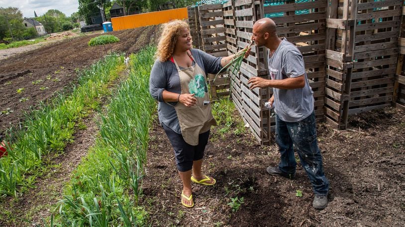 Erika Allen, left, co-founder and CEO of Urban Growers Collective at the South Chicago Farm in Schafer Park, samples fresh garlic grown by farmer Randy Toranzo, right, in Chicago, Ill. on Wednesday, May 30, 2018. (Zbigniew Bzdak/Chicago Tribune/TNS)