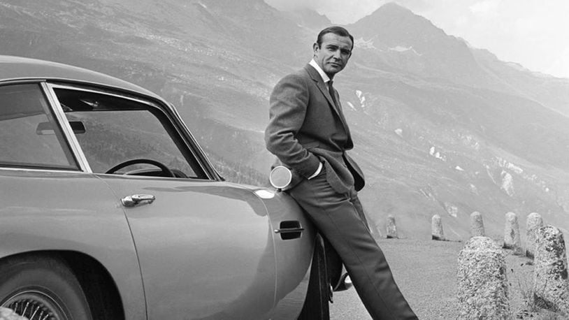 Actor Sean Connery poses as James Bond next to his Aston Martin DB5 in a scene from the 1964 film, "Goldfinger."