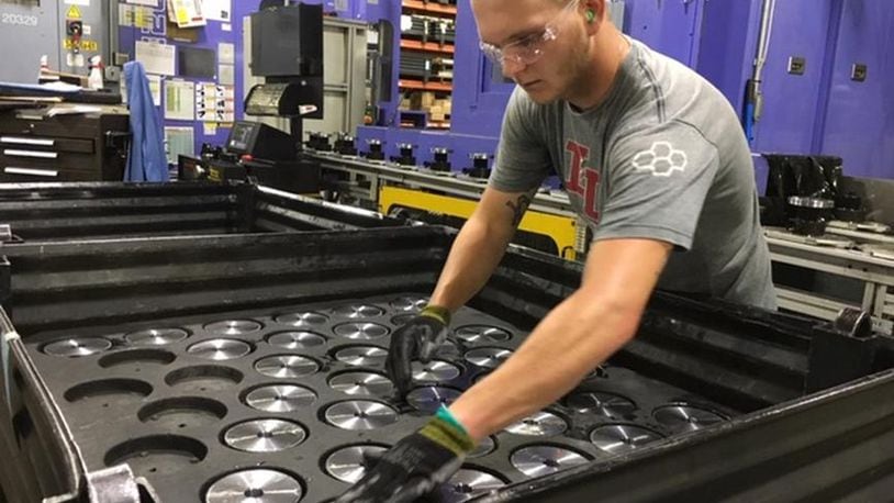 In a photo taken in July, Crown Equipment worker Michael Lensman arranges gears after cutting them on an assembly line in a New Bremen Crown facility. THOMAS GNAU/STAFF