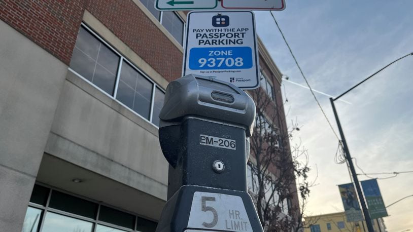 Signs have been installed around downtown Dayton advertising that people can pay for parking using the Passport Parking mobile app. But it's not operational yet. The pay-by-mobile device option is expected to formally launch in late March 2022. CORNELIUS FROLIK / STAFF