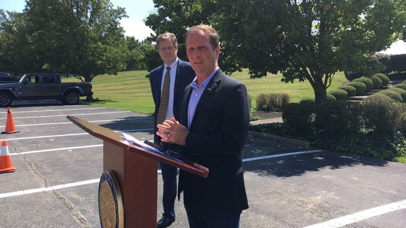 U.S. Rep. Chris Stewart, R-Utah, at a podium Tuesday outside the Hope Hotel at Wright-Patterson Air Force Base, with fellow Congressman Mike Turner, R-Dayton, looking on. THOMAS GNAU/STAFF