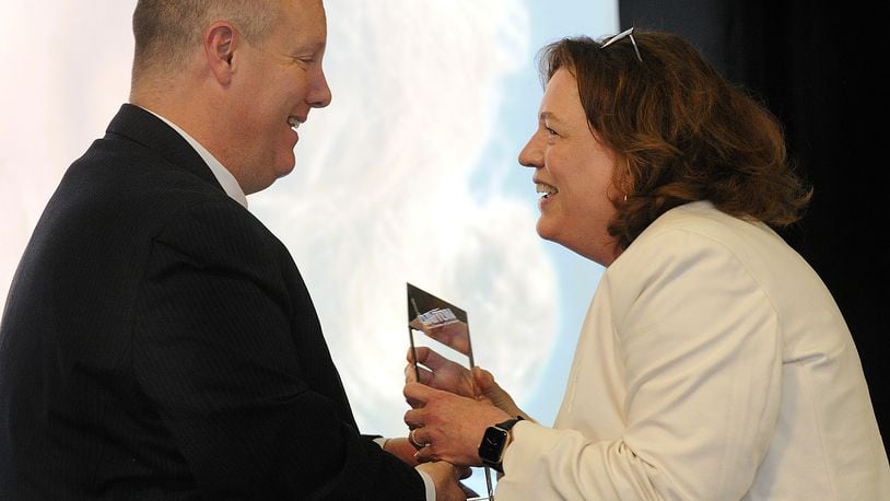 Chris Kershner hands Jana Collier, retired publisher of Cox First Media, the Dayton chamber's "Phillip Parker volunteer of the year" award at the Dayton Area Chamber 117th annual membership meeting Thursday, May 4, 2023. MARSHALL GORBY\STAFF