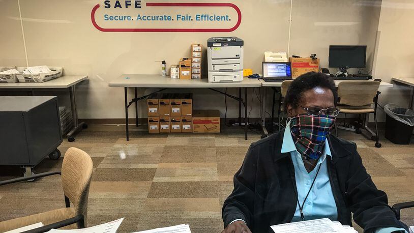 Seasonal staffer at the Montgomery County Board of Elections, Mary Ann Jones works behind a protective plastic shield that will help protect staff and voters during the pandemic as early voting begins Oct. 6, 2020.