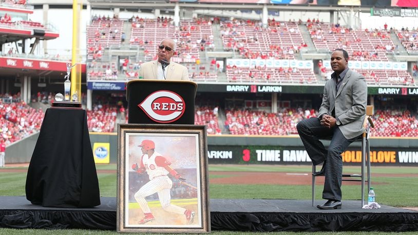 Reds radio announcer Marty Brennaman talks to the crowd while former shortstop Barry Larkin listens during the ceremony in which the team retired Larkin's number before the start of a game against the Cardinals at Great American Ball Park in 2012.