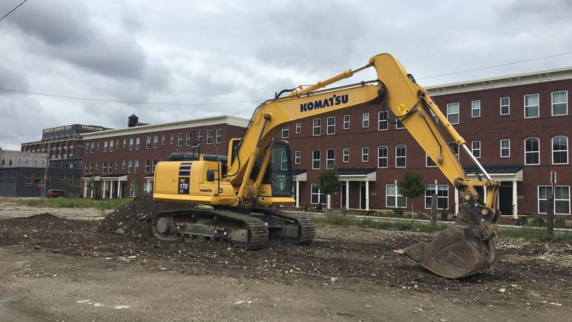 An excavator sits on the land between the commercial buildings on the 600 block of East Third St. and the Brownstones at 2nd townhouses. The land will become a parking lot to benefit redevelopment of the commercial buildings. CORNELIUS FROLIK / STAFF