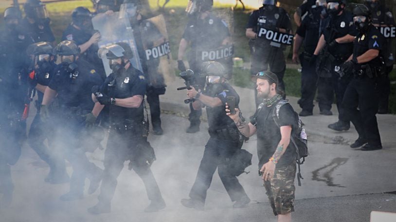 Dayton police deploy tear gas to disperse a crowd of protesters in July 2020 after some began to riot, damaging police cruisers and businesses in the city. MARSHALL GORBY / STAFF