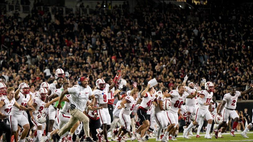 Miami players and coaches celebrate after a defensive back Yahsyn McKee intercepts the ball in the end zone during overtime of an NCAA college football game against Cincinnati, Saturday, Sept. 16, 2023, in Cincinnati. (AP Photo/Jeff Dean)