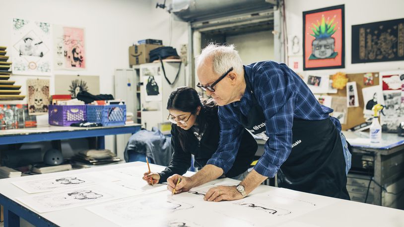 This image released by PBS shows actor John Lithgow, right, with Yoli, as they work on a screen print drawing during the filming of "Art Happens Here With John Lithgow," premiering April 26. (Antonio Diaz/PBS SoCal via AP)