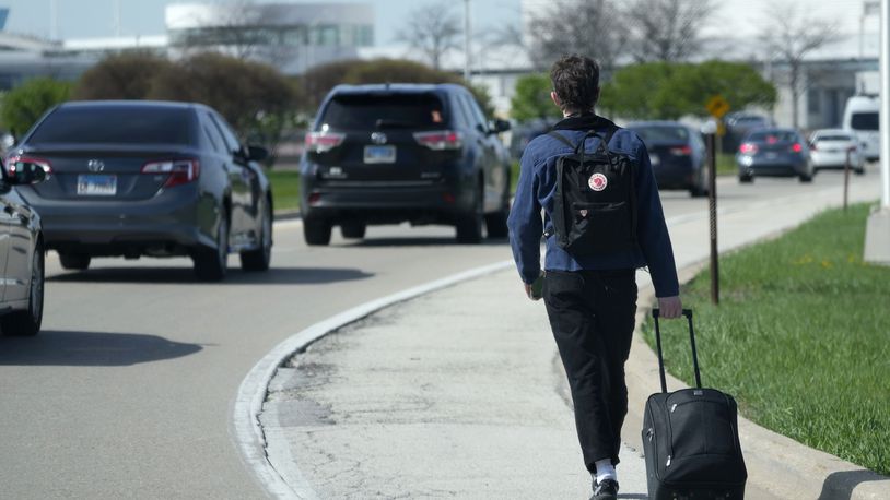 A passenger walks on the highway as he carries his luggage to at O'Hare International Airport in Chicago, Monday, April 15, 2024. Pro-Palestinian demonstrators blocked a freeway leading to three Chicago O'Hare International Airport terminals Monday morning, temporarily stopping vehicle traffic into one of the nation's busiest airports and causing headaches for travelers. (AP Photo/Nam Y. Huh)