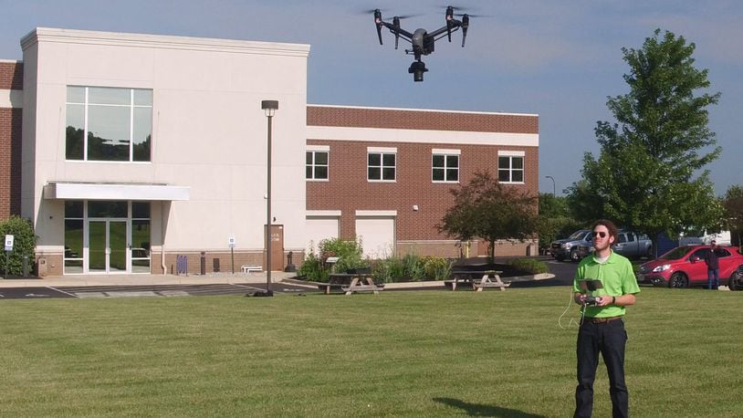 Ethan Schreuder, a survey technician and UAS pilot for Woolpert, flies an unmanned aerial systems craft outside Woolpert headquarters in the summer of 2018. FILE