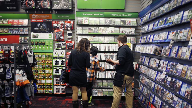 An employee assists customers shopping for Microsoft Xbox 360 video games inside a GameStop Corp. store in Louisville, Ky., on March 15, 2018. Bloomberg photo by Luke Sharrett.