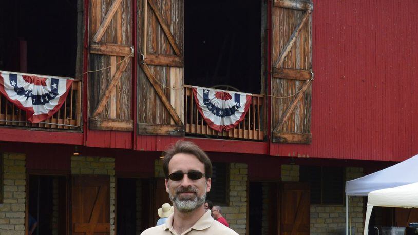 Michael Case has settled in to the role of Director of Programs and Properties for the Oxford Museum Association. He is shown with the Pioneer Barn in the background at last weekend’s Hueston Woods Arts & Crafts Fair. CONTRIBUTED/BOB RATTERMAN