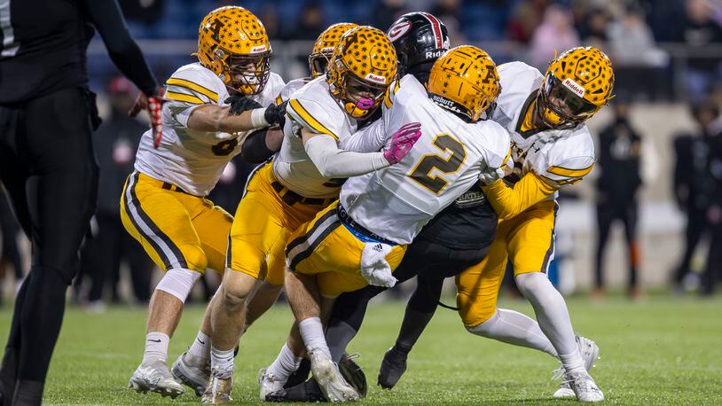 A group of Alter players make a tackle during the Division IV state championship game against Cleveland Glenville on Saturday night at Tom Benson Hall of Fame Stadium in Canton. CONTRIBUTED PHOTO BY MICHAEL COOPER