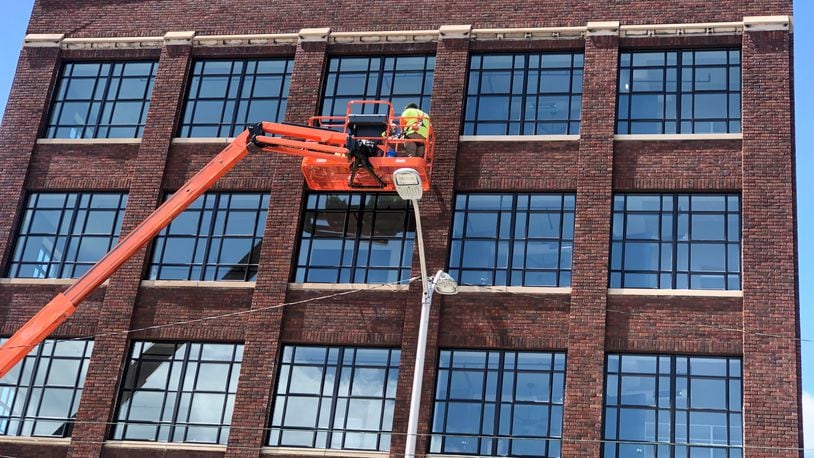 Crews work on the exterior of the Graphic Arts Lofts building in downtown Dayton on Monday. CORNELIUS FROLIK / STAFF
