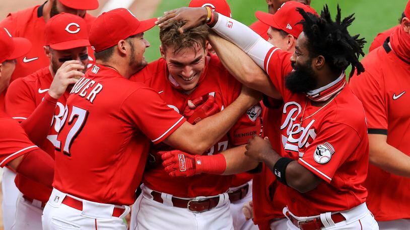 Cincinnati Reds' Trevor Bauer, left, hugs Tyler Stephenson, center, after Stephenson hit a walkoff two-run home run in the seventh inning while Brian Goodwin, right, reacts during a baseball game against the Pittsburgh Pirates in Cincinnati, Monday, Sept. 14, 2020. (AP Photo/Aaron Doster)