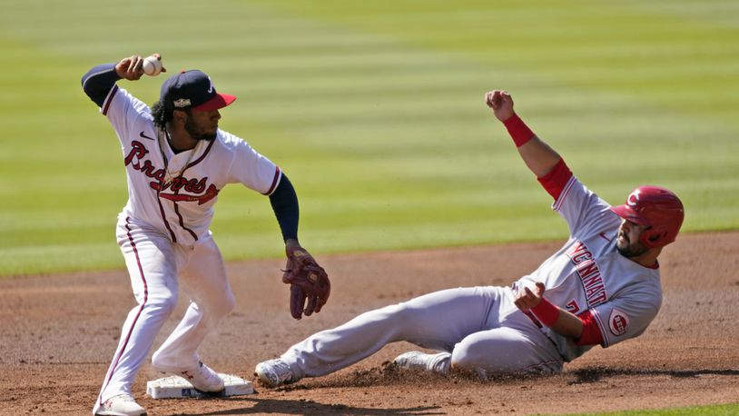Atlanta Braves second baseman Ozzie Albies (1) throws to first after forcing out Cincinnati Reds' Eugenio Suarez (7) during the second inning in Game 2 of a National League wild-card baseball series, Thursday, Oct. 1, 2020, in Atlanta. The Reds' Mike Moustakas was safe at first. (AP Photo/John Bazemore)