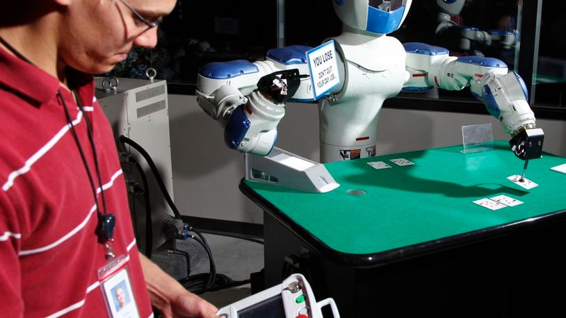 Attracting more foreign-owned companies — such as Yaskawa Motoman in Miamisburg — was a rationale for a vote Friday to fully fund a Canadian company’s plan to move its U.S. headquarters to the Dayton area. In this file photo, Yaskawa Motoman co-op worker Greg Smith checks the programming of a two-armed robot that plays Blackjack in the company’s showroom. TY GREENLESS/STAFF