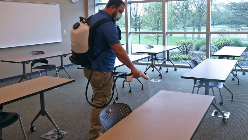Ryan Green, Maintenance Supervisor at Clark State, sanitizes a classroom with a Protexus Electrostatic Sprayer like his crew will do every evening when classes are finished. Students are also positioned six feet apart in the classrooms and hand sanitizers are outside every classroom. BILL LACKEY/STAFF