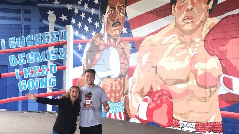 Jerri Stanard, founder/owner of K12 Gallery & TEJAS and her son, UD Student and Flyers boxer Jackson Stanard, the artist who drew the mural and did much of the work putting it on wall at Drake’s Downtown Gym. He’s one of the members of the newly formed UD boxing team. Tom Archdeacon/CONTRIBUTED
