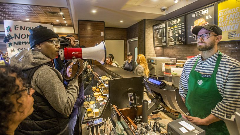 Local Black Lives Matter activist Asa Khalif, left, stands inside the Starbucks at 18th and Spruce, and over a bullhorn, demands the firing of the manager that called police, which resulted in two black men being arrested. On Sunday April 15, 2018, protesters demonstrated outside the Starbucks and planned to return Monday. (Michael Bryant//Philadelphia Inquirer/TNS)