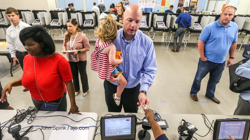 Neal Norris and his daughter Piper, 1, as the polls open at Hammond Drive Gym in Sandy Springs on Tuesday, June 20, 2017.