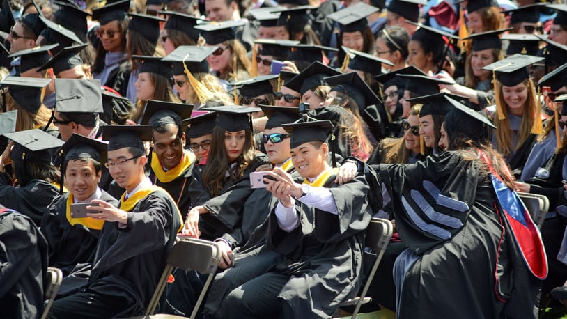 Graduates pause to make selfie pictures during commencement.