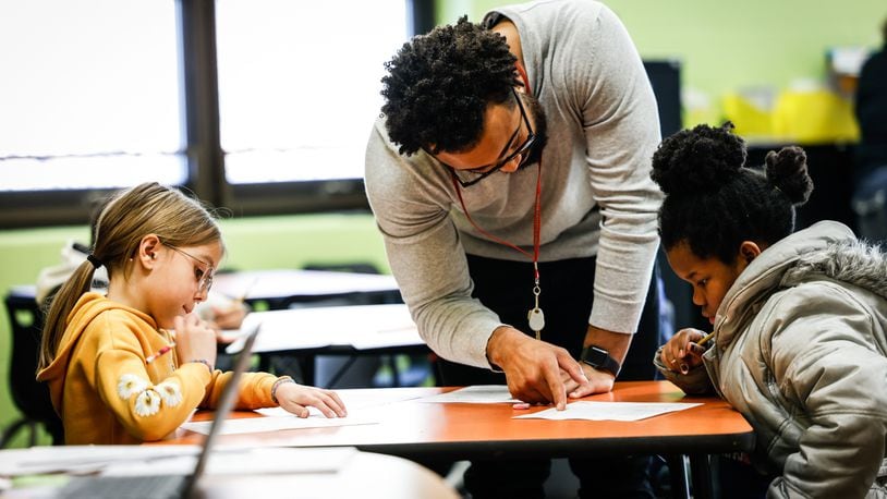 Third-grade tutor Tyree Kinnel helps Arayna Ruble, left, and Brooklynn Guy at Charles Huber Elementary School Tuesday, Feb, 15, 2022. Huber Heights is one of two districts using additional teachers to help kids catch up on learning loss from the pandemic. JIM NOELKER/STAFF