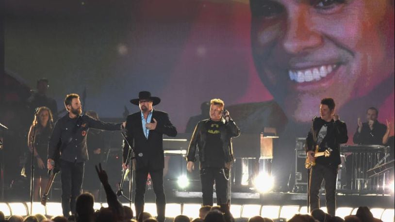 Country music artists (L-R) Dierks Bentley, Eddie Montgomery, Gary LeVox, and Jay DeMarcus perform onstage at the 51st annual CMA Awards at the Bridgestone Arena on November 8, 2017 in Nashville, Tennessee with an image of Troy Gentry, who died in a helicopter crash in September of 2017, on a big screen behind them.