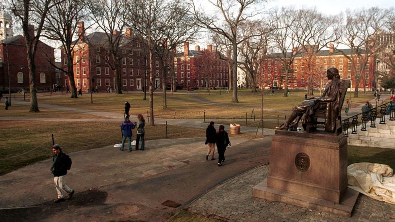 People walk past the John Harvard statue at Harvard University''s main campus December 19, 2000 in Cambridge, MA.
