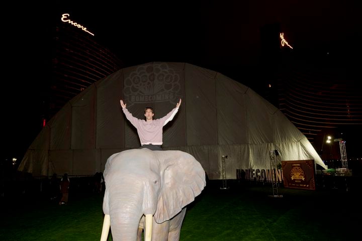 A partier celebrates from atop an elephant statue outside a 45,000-square-foot tent where h.wood Group, a hospitality business, was hosting a Super Bowl party, in Las Vegas, just before midnight on Feb. 9, 2024. (Bridget Bennett/The New York Times)