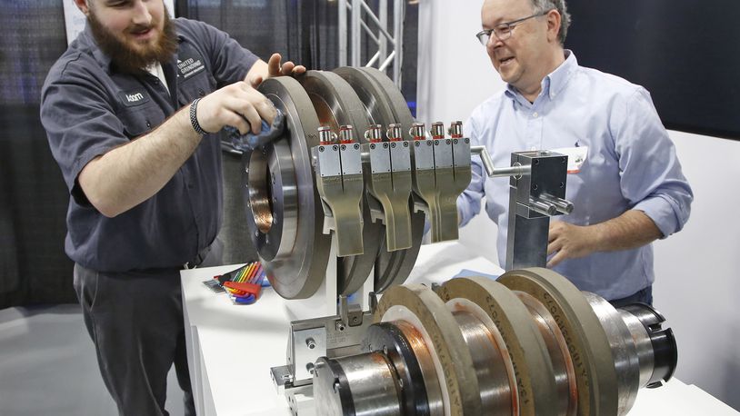 Manufacturing technician Adam Fox, left, and international sales representative Ralf Schuerl prepare centerless grinding machine parts for display at United Grinding in this photo from April 2018. TY GREENLEES / STAFF