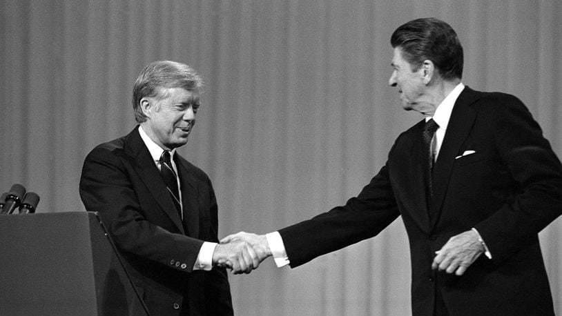 FILE - This Oct. 28, 1980 black-and-white file photo shows President Jimmy Carter, left, and Republican Presidential candidate Ronald Reagan shake hands after debating in the Cleveland Music Hall in Cleveland. In presidential politics, everybody’s searching for “the moment.” The campaigns don’t know when or how it will come, but they watch for something _ awkward words or an embarrassing image _ that can break through and become the defining symbol of the other guy’s flaws. Now all eyes are on the series of three presidential debates that starts Wednesday. (AP Photo/Madeline Drexler, File)