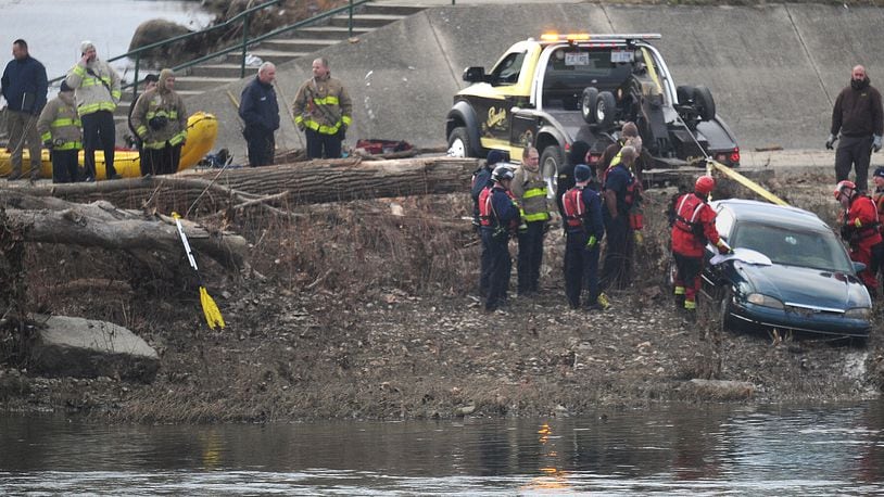 A team from the Dayton Fire Department responded to the Great Miami River just after 2 p.m. on Monday to search for a vehicle that was spotted in the water. A tow truck helped to recover the vehicle, and a sheet was placed on the back window as it emerged from the water. MARSHALL GORBY/STAFF