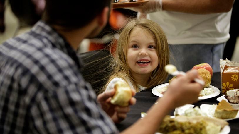 Faith Marie Oakes, 4, enjoys dinner with her father Eric Anders of Dayton during the Feast of Giving, an annual event held each Thanksgiving Day at the Dayton Convention Center. LISA POWELL / STAFF PHOTO