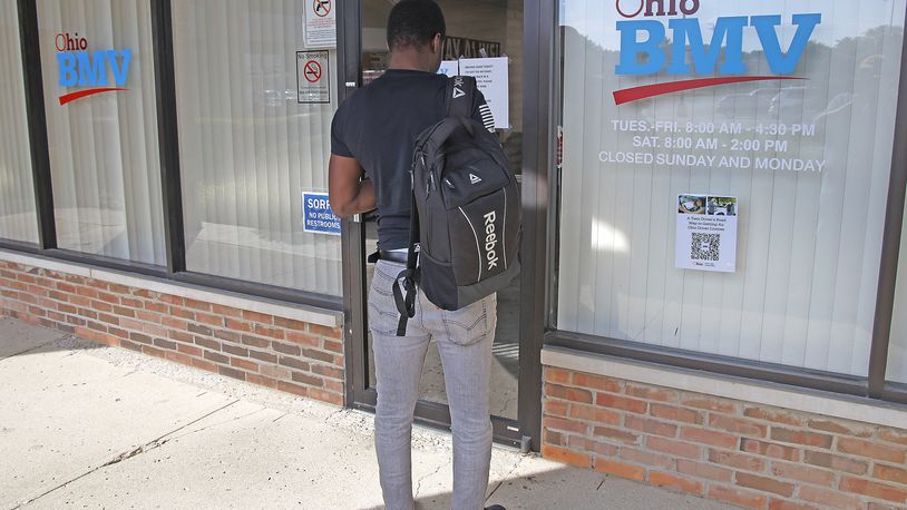 A man reads a sign on the door of the Ohio BMV testing center in the Park Shopping Center on Thursday, Sept. 21, 2023. BILL LACKEY/STAFF