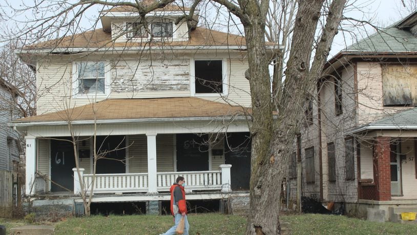 A pedestrian walks by blighted homes in north Dayton. CORNELIUS FROLIK / STAFF