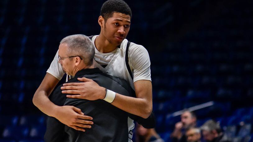 Centerville's Mo Njie hugs head coach Brook Cupps as he comes off the court after fouling out in their Division I Regional boys basketball semifinal March 11, 2020 at Xavier University's Cintas Center. In an effort to reduce the risk of spreading coronavirus (COVID-19), players were allowed to designate 4 family members to purchase tickets for the game and coaching staff was allowed 2 family members each. NICK GRAHAM / STAFF