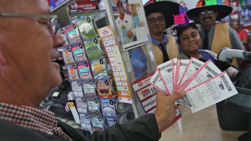 Cole Barker looks over the Mega Millions lottery tickets he just purchased on Thursday. The Mega Millions jackpot is expected to grow to at least to $1.6 billion for Tuesday’s drawing. BILL LACKEY/STAFF